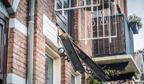 Balkon met vader en zoon erop stort neer